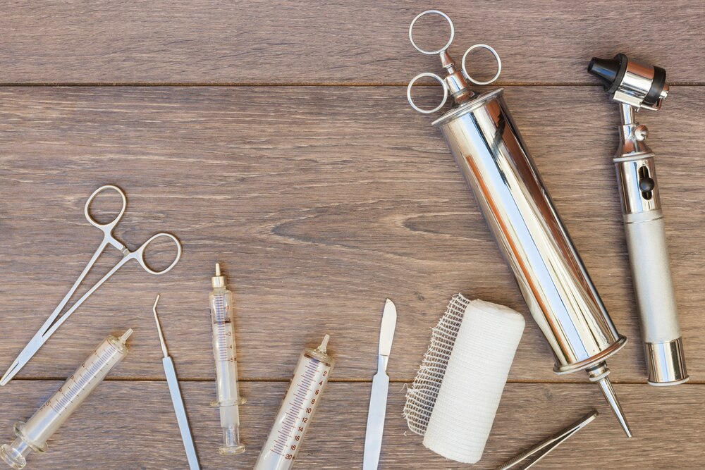 Vintage stainless steel syringe; otoscope and medical equipment's on wooden desk
