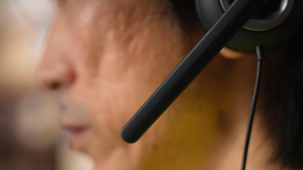 Close up of male staff answers help line calls in a logistics depot updating clients on orders and